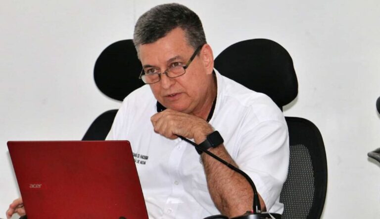 Persona sentada hablando por un microfono en mano.
