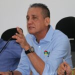 persona sentada, con una mano alzada