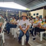 Grupo de personas y una sentada de frente con sombrero y camiseta blanca